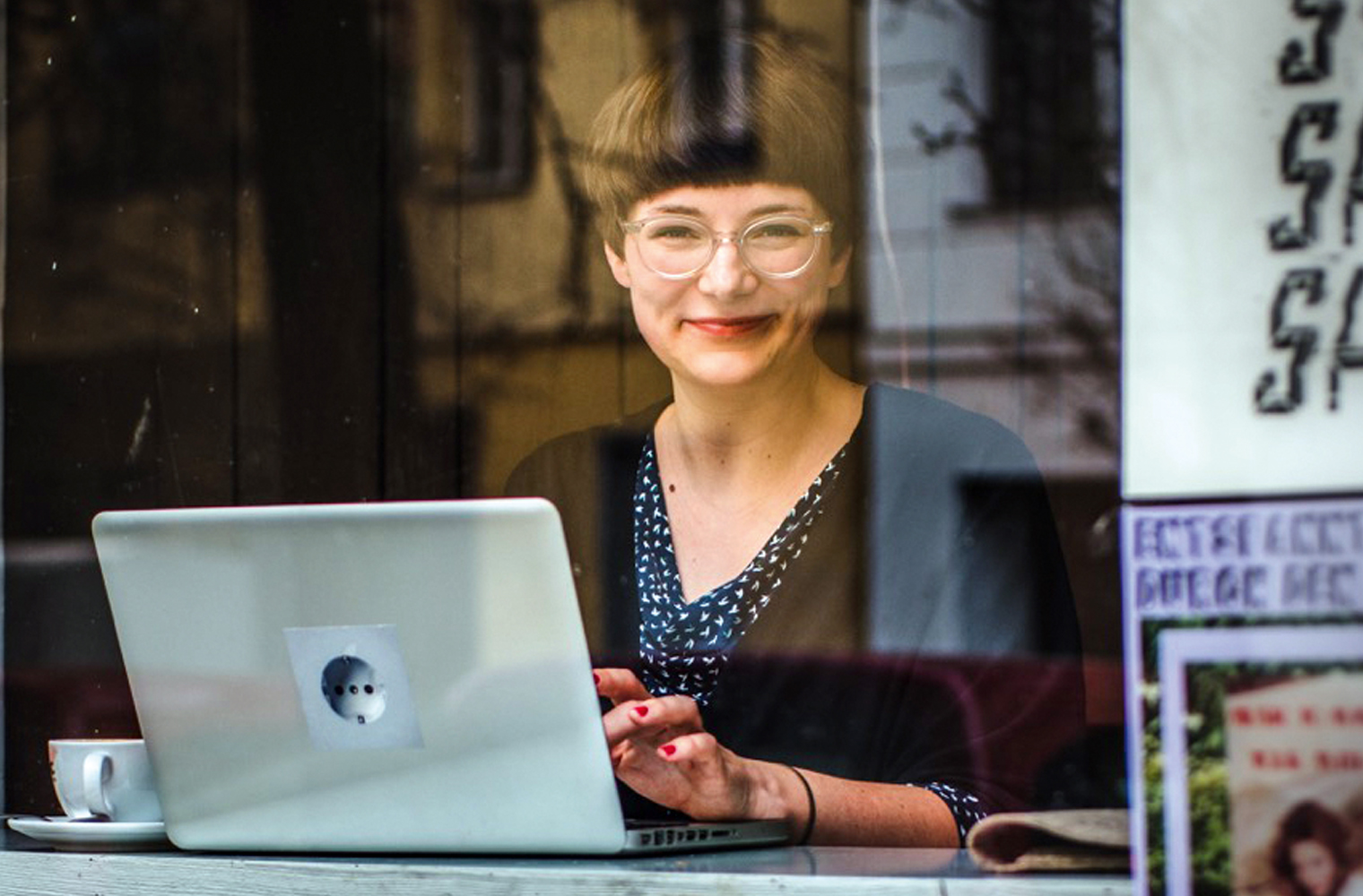 Die Journalistin und Bloggerin Mareice Kaiser sitzt hinter einem großen Fenster und arbeitet am Computer. - Foto: Carolin Weinkopf